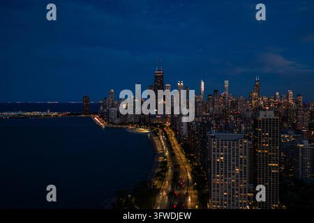 Vista aerea notturna della skyline illuminata di Gold Coast e di Lake Shore Drive con scie di luce lungo la riva oscura del lago Michigan, Chicago Foto Stock