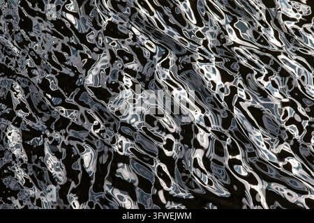 Vista di riflessi d'acqua astratti sulla superficie del canale IJ vicino all'edificio Sluishuis ad Amsterdam, Olanda Settentrionale, Paesi Bassi. Foto Stock