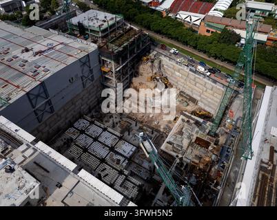 Vista aerea di un grande cantiere edile accanto a edifici commerciali esistenti. Foto Stock