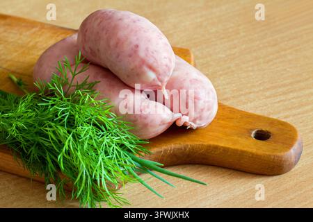Salsicce di carne fatte in casa con erbe su un tagliere. Salsicce crude in primo piano. Foto Stock