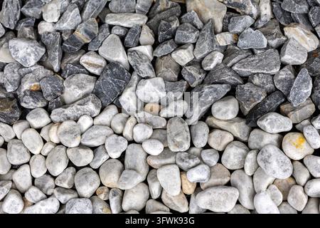 Primo piano di pietre di ghiaia decorative grigie e bianche disposte in un motivo naturale strutturato, strati contrastanti di rocce scure ruvide e pietre chiare lisce Foto Stock