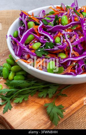 Prima piano dettagliata di un'insalata fresca di cavolo rosso e carote con fagioli di edamame verdi, prezzemolo e semi di sesamo, che mostra colori vivaci e una consistenza croccante Foto Stock