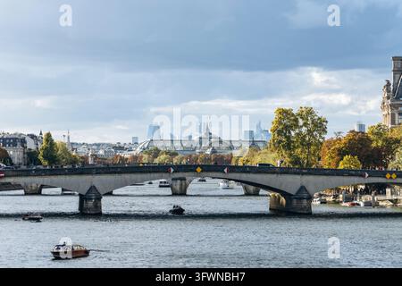 Parigi, Francia - 10 ottobre 2026: Barche navigano lungo la Senna sotto il ponte storico di Pont Royal, con il Grand Palais e il fogliame autunnale Foto Stock