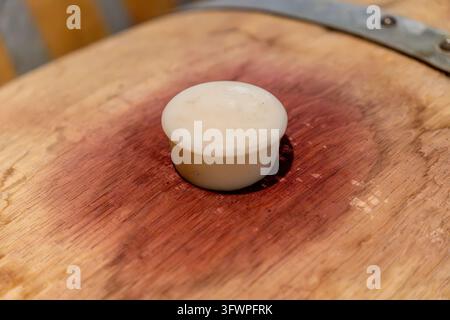 Tappo di plastica bianco che sigilla una botte di vino in legno, con macchie di vino rosso intorno al tappo, indicanti fermentazione Foto Stock