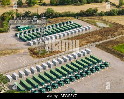 Contenitori di batterie su larga scala in un campo rurale gestiscono l'alimentazione regionale e supportano le energie rinnovabili. Foto Stock