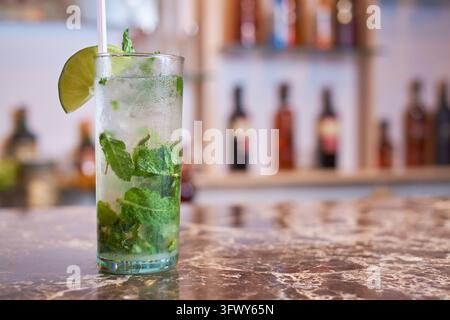 Mojiti di frutta colorati con menta, lime e ghiaccio tritato in bicchieri alti su un bancone di marmo. Foto Stock