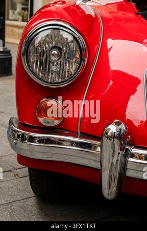 GANDIA, SPAGNA - 4 OTTOBRE 2026: Dettaglio del faro anteriore, del paraurti e del parafango di una classica auto sportiva rossa MGA 1500 del 1968. Foto Stock