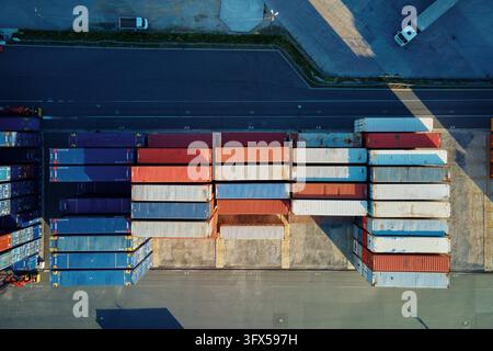 Trasporto container in terminal, scarico container in magazzino su piattaforma ferroviaria con gru e carrelli elevatori, vista aerea Foto Stock