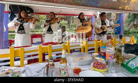 Xochimilco è noto per la sua rete di canali e per le trajineras dipinte di colori vivaci, dove i visitatori possono assumere musicisti per suonare a bordo delle barche. Foto Stock