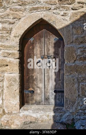 Antica porta ad arco in legno con battenti in ferro e un lucchetto arrugginito, inserita in un muro di pietra storico del castello di Mardakan a Baku, in Azerbaijan Foto Stock