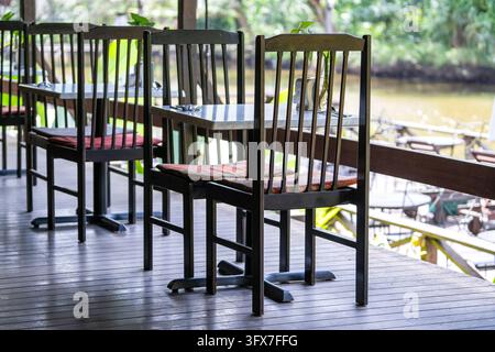 Sedie e tavolo in legno sul cortile nel caffè tropicale vicino al lago con splendida vista sull'isola del Borneo, Malesia, da vicino Foto Stock