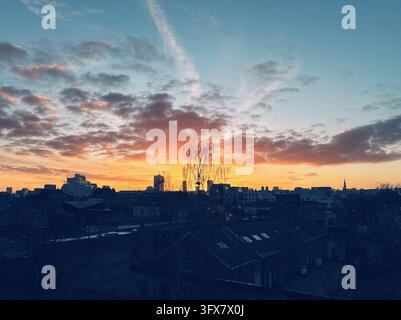 Bellissimo cielo mattutino con nuvole colorate arancioni e rosa all'alba sulla silhouette scura del paesaggio urbano di Bruxelles. Foto Stock