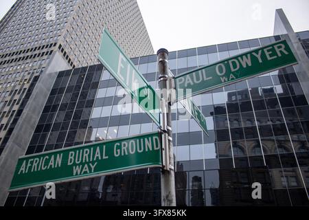 Manhattan, New York City, USA – 24 dicembre 2023: Cartelli stradali con la scritta African Burial Ground Way e Paul O'Dwyer Way ad un angolo sotto torri di vetro. Foto Stock