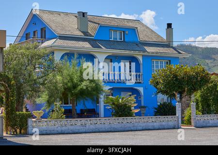 Casa residenziale blu brillante con balconi e giardino curato. Ribadeo, Lugo, Spagna - 31 agosto 2026. Foto Stock