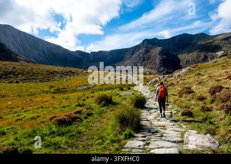 Persona con uno zaino che fa escursioni su un sentiero di pietra nelle montagne Foto Stock