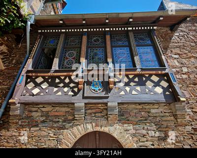 Vista dettagliata di un balcone in legno intagliato con finestre a vetrate colorate e stemma araldico al castello di Reichsburg Cochem a Cochem, Germania. Foto Stock