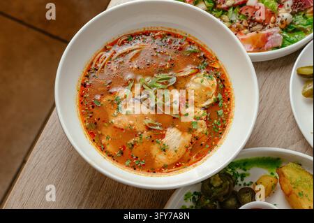 Una deliziosa ciotola di zuppa di noodles al pollo piccante su un tavolo Foto Stock