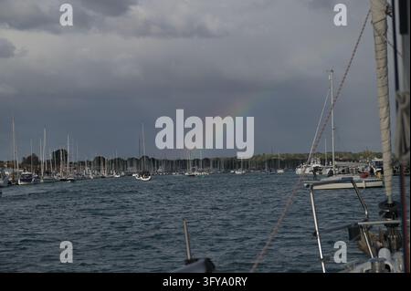 Arcobaleno sulle barche ormeggiate sotto un cielo tempestoso, Yarmouth, Isola di Wight, Regno Unito, 18 ottobre 2026 Foto Stock