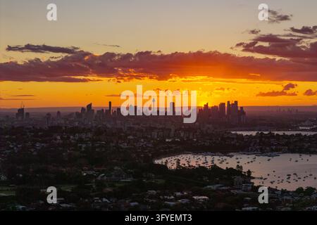 Vista aerea dello skyline di Sydney al tramonto con il sole che tramonta dietro i grattacieli e barche ancorate nella baia, Sydney, Nuovo Galles del Sud, Austra Foto Stock