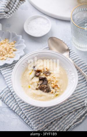 Zuppa cremosa di cavolfiore con fette di funghi scuri in un'elegante ciotola bianca Foto Stock