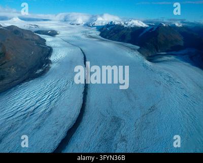 Una vista panoramica elevata che si affaccia sulla baia di Aialik al tramonto, catturando il drammatico paesaggio glaciale del campo di ghiaccio Harding e del ghiacciaio Exit nel parco nazionale dei Kenai Fjords, Alaska, USA. La luce dorata del sole bagna la vasta distesa di neve, le vette delle montagne e le formazioni di ghiaccio frastagliate, evidenziando la natura selvaggia e la maestosità naturale della regione dei fiordi costieri dell'Alaska. Una versione ottimizzata di un'immagine del US National Park Service. Credit: NPS / D Kurtz Foto Stock