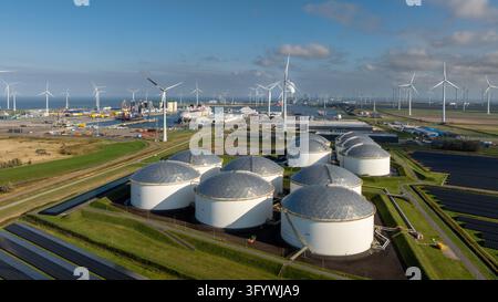 Vista aerea del porto marittimo di Eemshaven con grandi serbatoi di stoccaggio bianchi, turbine eoliche e infrastrutture industriali a Eemshaven, Groninga, Paesi Bassi Foto Stock