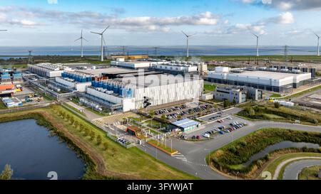 Vista aerea della struttura del centro dati Google con grandi edifici industriali, turbine eoliche e infrastrutture circostanti a Eemshaven, Groningen Foto Stock