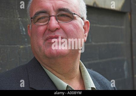 Ritratto di un casualmente vestito uomo d affari in piedi contro un muro di pietra Foto Stock