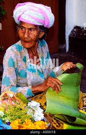 Donna locale vendita di fiori freschi alla sua pressione di stallo nel mercato di denpasar Bali Indonesia Foto Stock