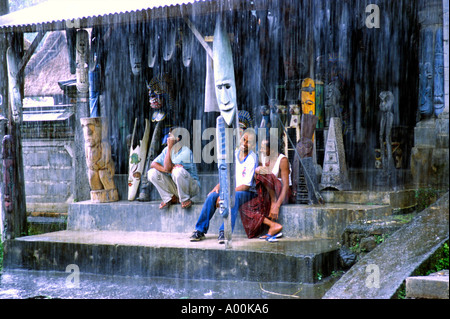 Gli uomini locali guardano fuori dal loro negozio facciata come la pioggia si riversa all'esterno in Ubud Bali Indonesia Foto Stock