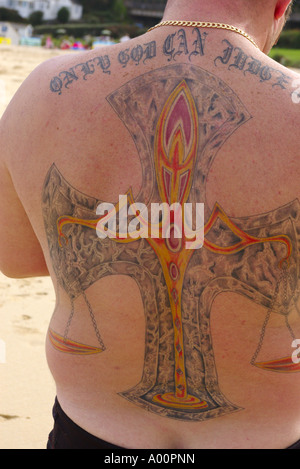 Un uomo avente un grande tatuaggio sulla schiena su una spiaggia Cornwall Regno Unito Foto Stock