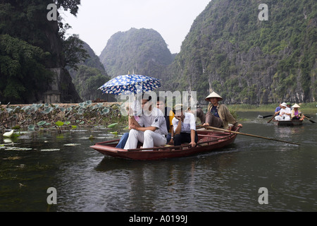 I visitatori in viaggio in barca per Tam Coc grotte con piedi canottaggio boatman Ngo Dong fiume vicino a Ninh Binh Vietnam del nord Foto Stock