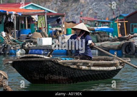 Cappello conico righe donna tessuto tradizionale in barca attorno a floating villaggio di pescatori Cat Ba Town Bay a nord-est del Vietnam Foto Stock