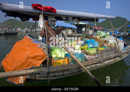 Donna con barca a remi il negozio di drogheria vende intorno a floating villaggio di pescatori Cat Ba Town Bay a nord-est del Vietnam Foto Stock