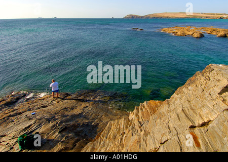 Fisherman su rocce esposte a bassa marea a Treyarnon Bay North Cornwall con testa Trevose all'orizzonte Foto Stock