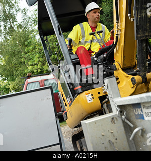 Ingegnere di acqua si siede nella cabina di un trattore JCB Foto Stock