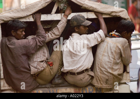 Camion indiano pieno di persone che viaggiano attraverso Himachal Pradesh, India. Uomini seduti sul retro di un veicolo coperto durante un viaggio. Foto Stock