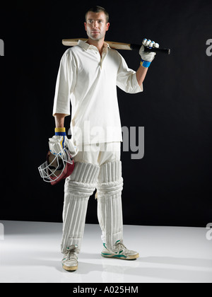 Giocatore di cricket, in piedi tenendo la bat sullo spallamento Foto Stock