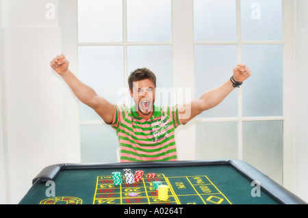 Giovane uomo celebrando sul tavolo della roulette Foto Stock