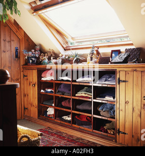 Vestiti in legno aperto ripiani montati sotto la finestra velux in mansarda camera da letto Foto Stock