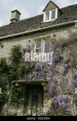 Il Glicine in fiore sulle pareti di una casa del villaggio Costwold di grande Rissington su una giornata di primavera Foto Stock