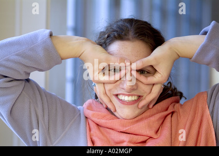 Giovane donna con le dita intorno agli occhi facendo una faccia buffa Foto Stock