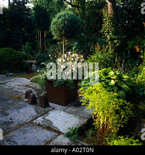 Pavimentazione in parte anteriore del giardino estivo confine con piccola struttura ritagliata e rosa rosa Foto Stock