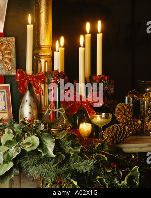 Close-up di edera e foglie di conifere con pigne e candele su mantelpiece decorato per il Natale con le candele Foto Stock