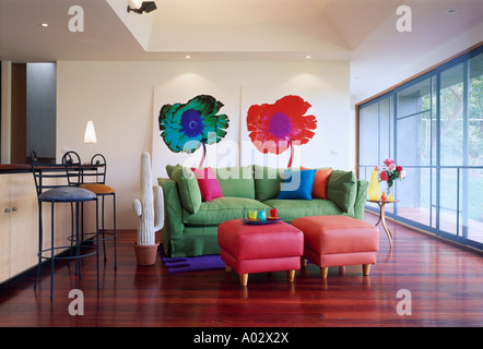 Le foto sulle pareti sopra vivacemente colorato divano e sgabelli in moderna casa cittadina livingroom Foto Stock