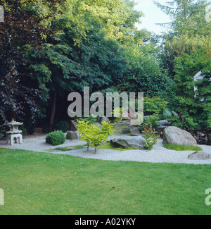 Oriental giardino roccioso con ghiaia rastrellata davanti di alberi di alto fusto comprendente un faggio di rame Foto Stock