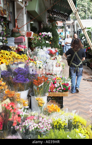 La gente camminare passato fioraio, il mercato dei fiori Foto Stock