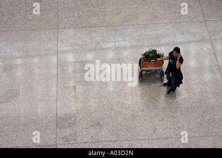 Donna che parla al cellulare all'Aeroporto Internazionale di Hong Kong Foto Stock