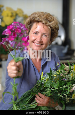 Una femmina di giardiniere CON I FIORI RECISI IN UNA CUCINA DI PAESE REGNO UNITO Foto Stock