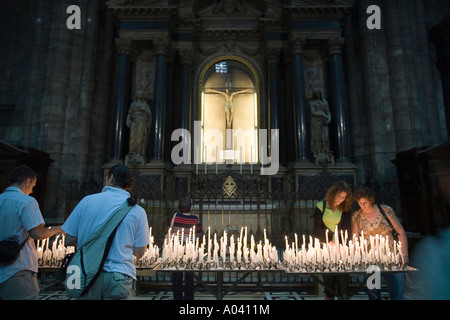Persone posizionare le candele accese nella cremagliera in un altare laterale al Duomo Milano Italia Foto Stock